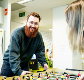 Two students playing foosball at ACAP Brisbane campus, with one student smiling towards camera