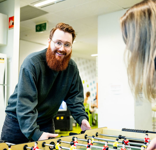 Two students playing foosball at ACAP Brisbane campus, with one student smiling towards camera