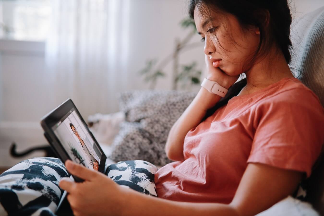 A woman in bed while watching something on a tablet.
