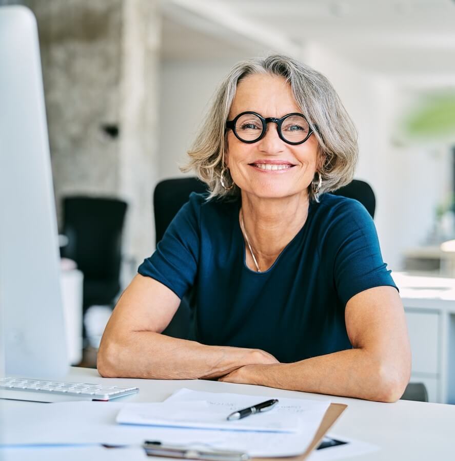 A woman sitting at a desk with paperwork in front of her.