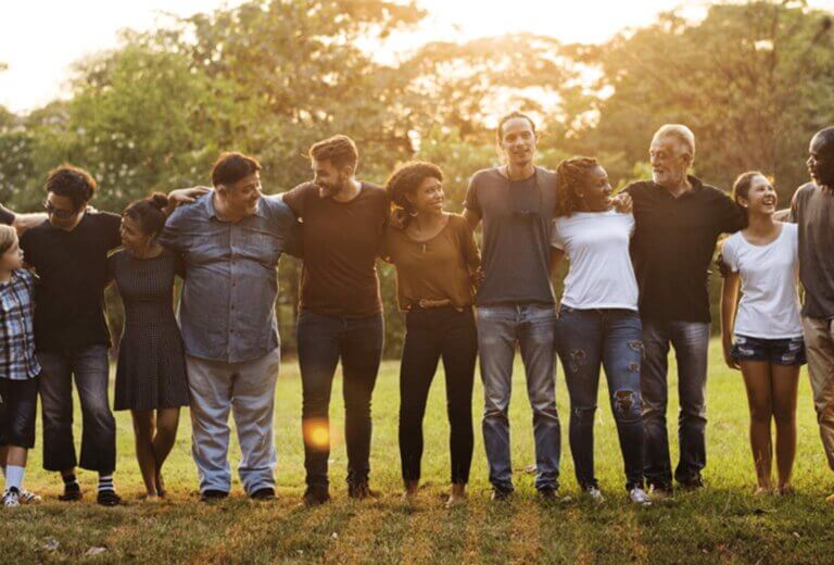 people standing in a line. in a park. arm in arm. sunset behind