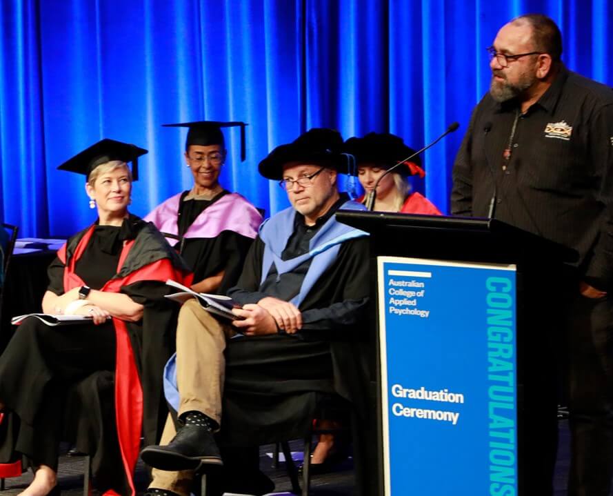 A man standing and giving a speech at a graduation event.