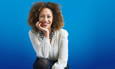 A woman smiling with her chin resting on the palm of her hand.