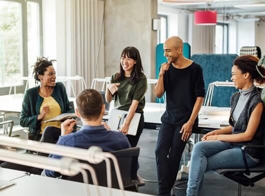 A group of people happily discuss something in the office.