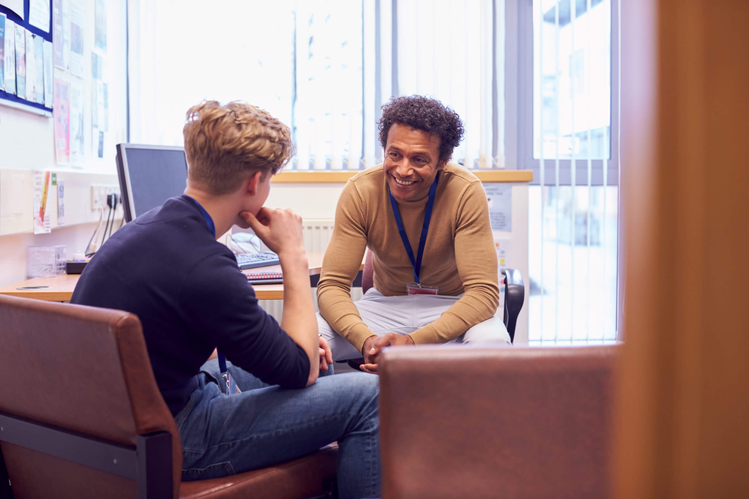 Male counsellor teacher talking to young male patient student