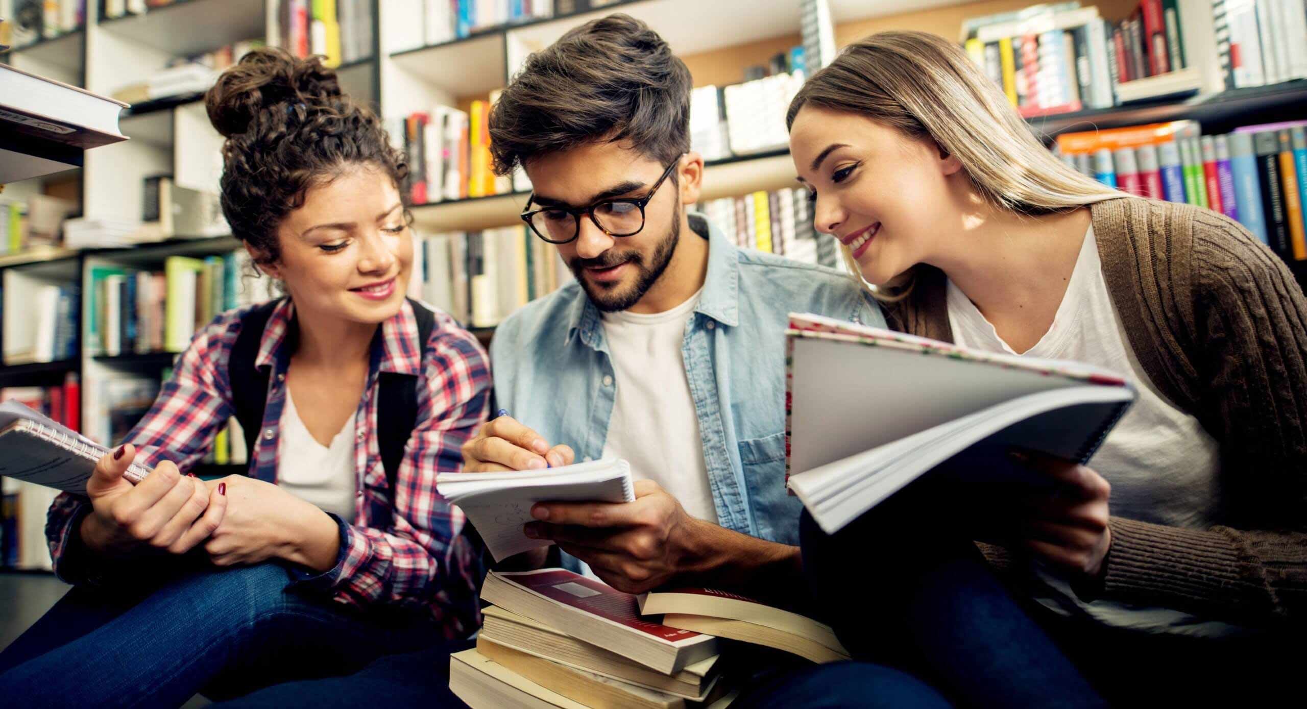 Three people happily discuss something at a library.