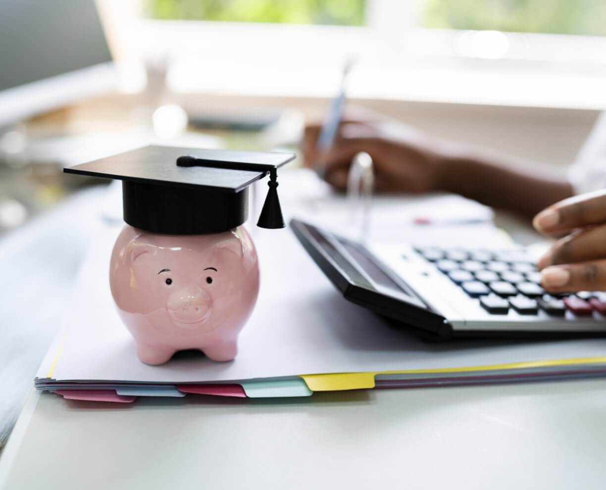 Fee Schedule Image of a desk with calculator and little porcelain pig statue.