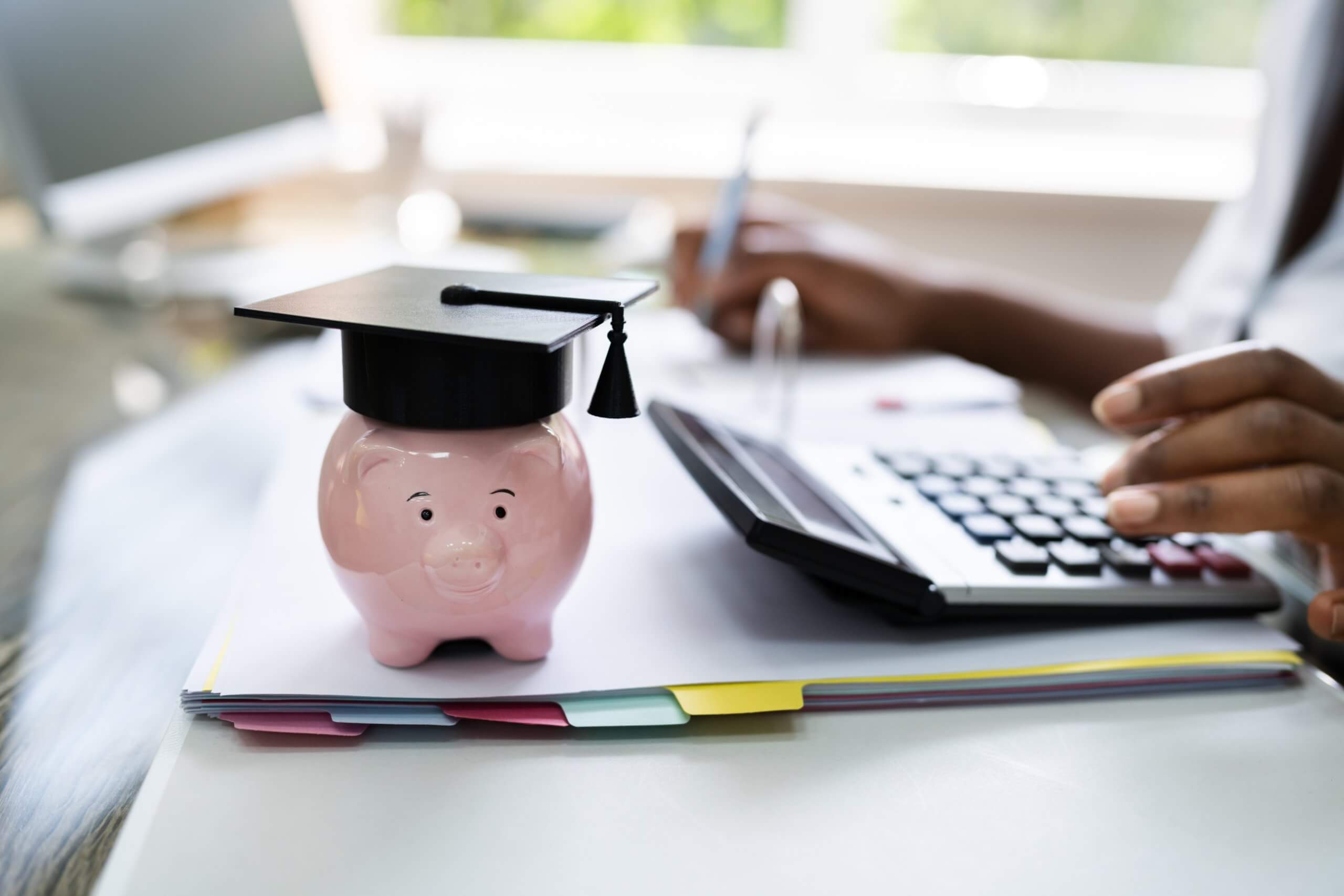 Image of a desk with calculator and little porcelain pig statue.