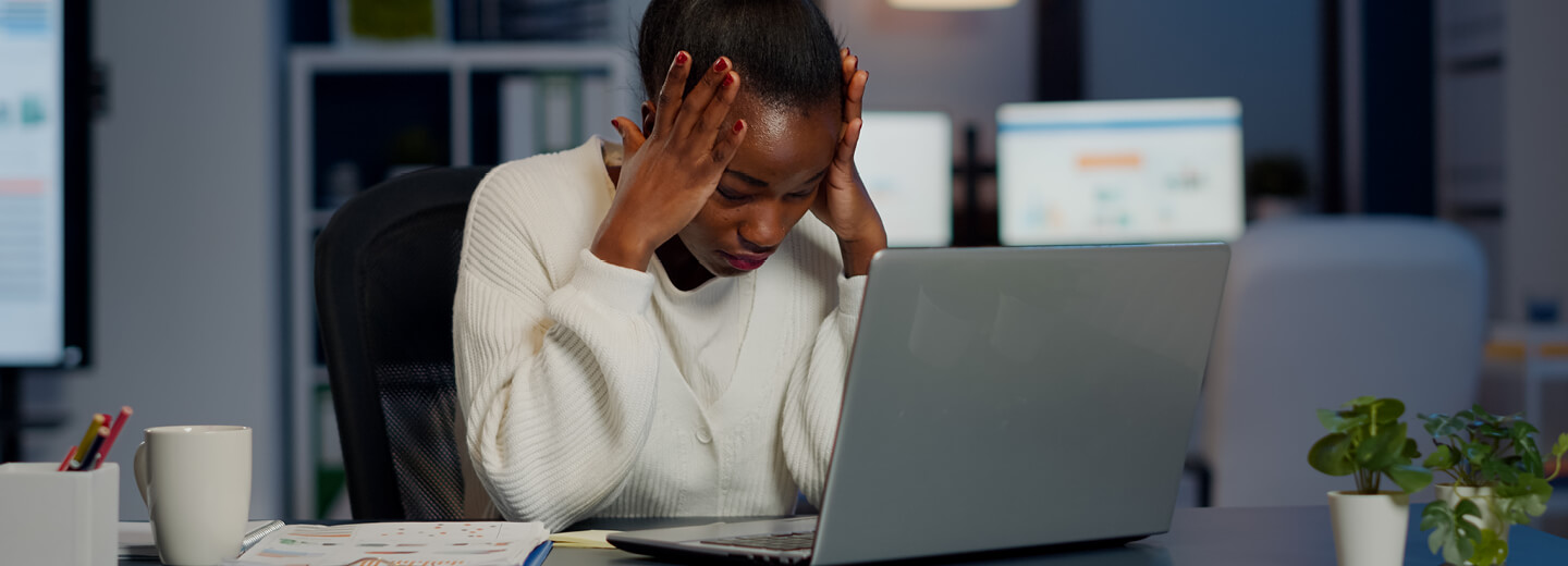 Woman with hands on head in front of laptop