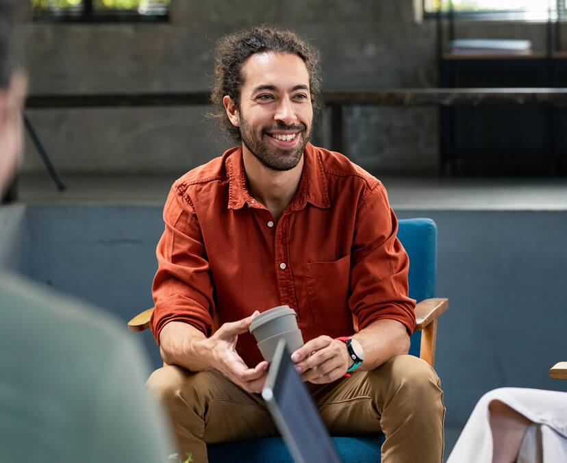 Man sitting down with coffee smiling