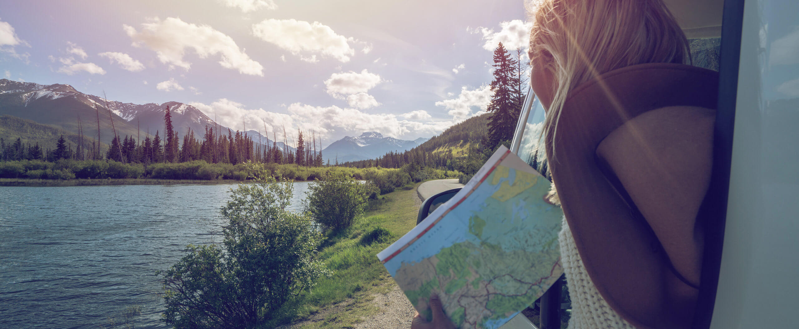 Photo of woman holding a map looking at a beautiful landscape