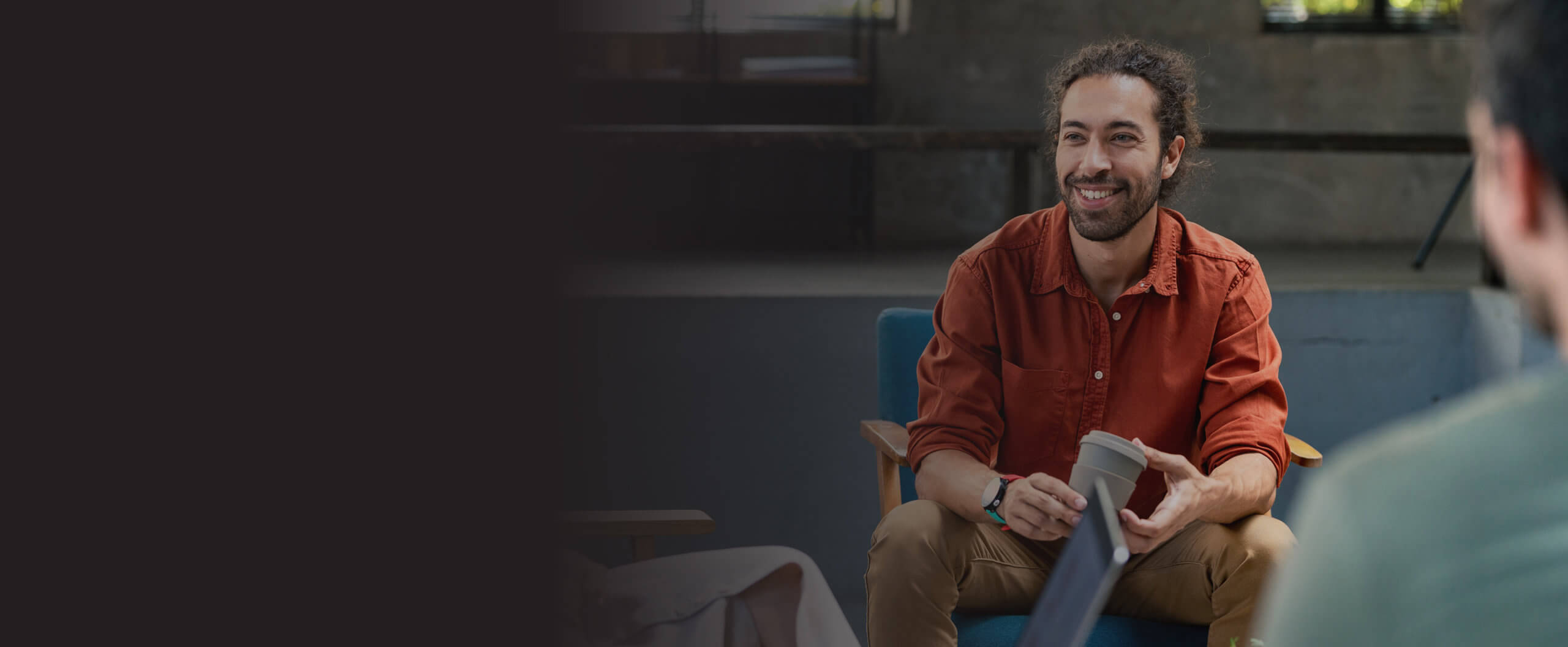 Man sitting on a chair listening to others smiling