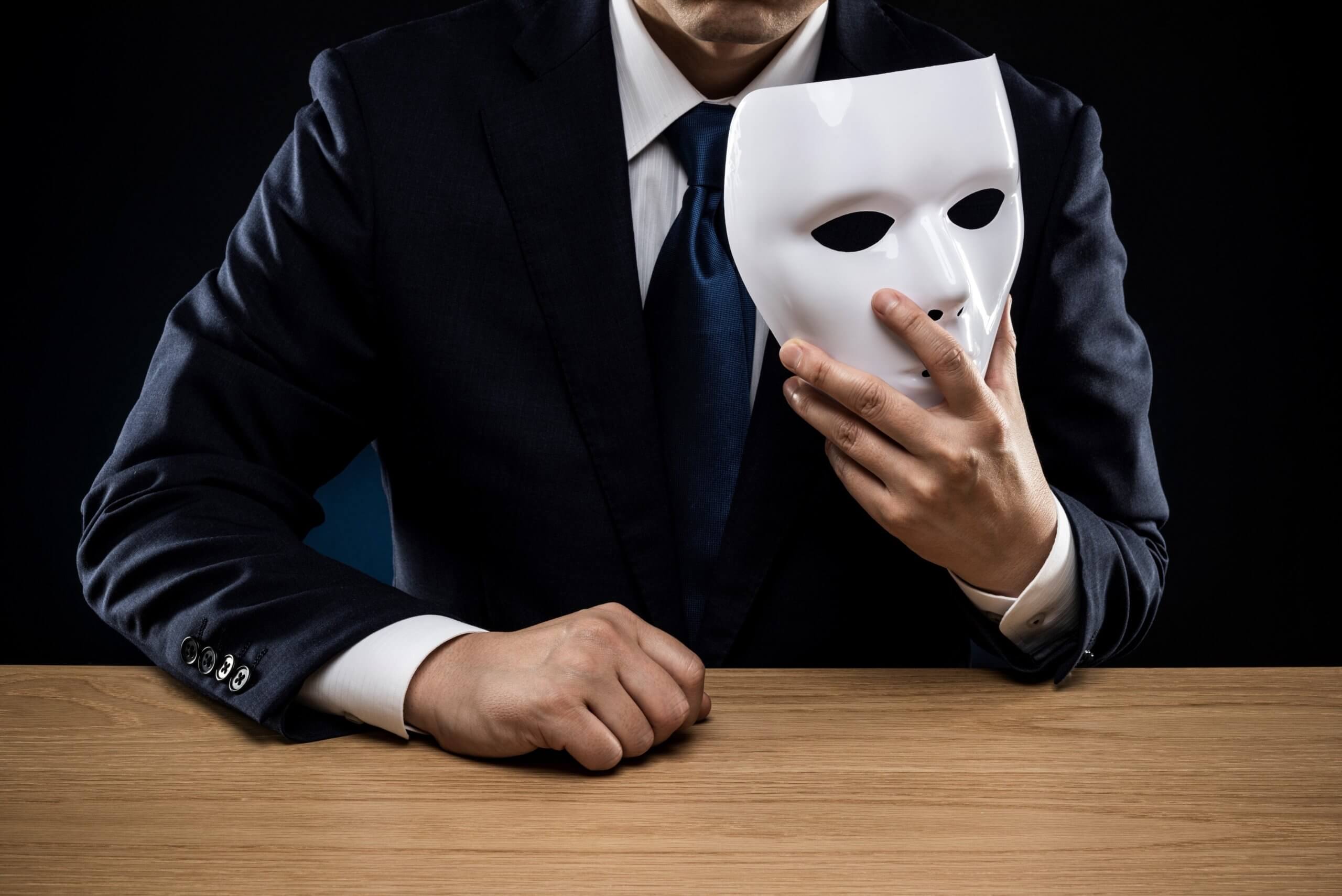 A hidden man holding a white mask.