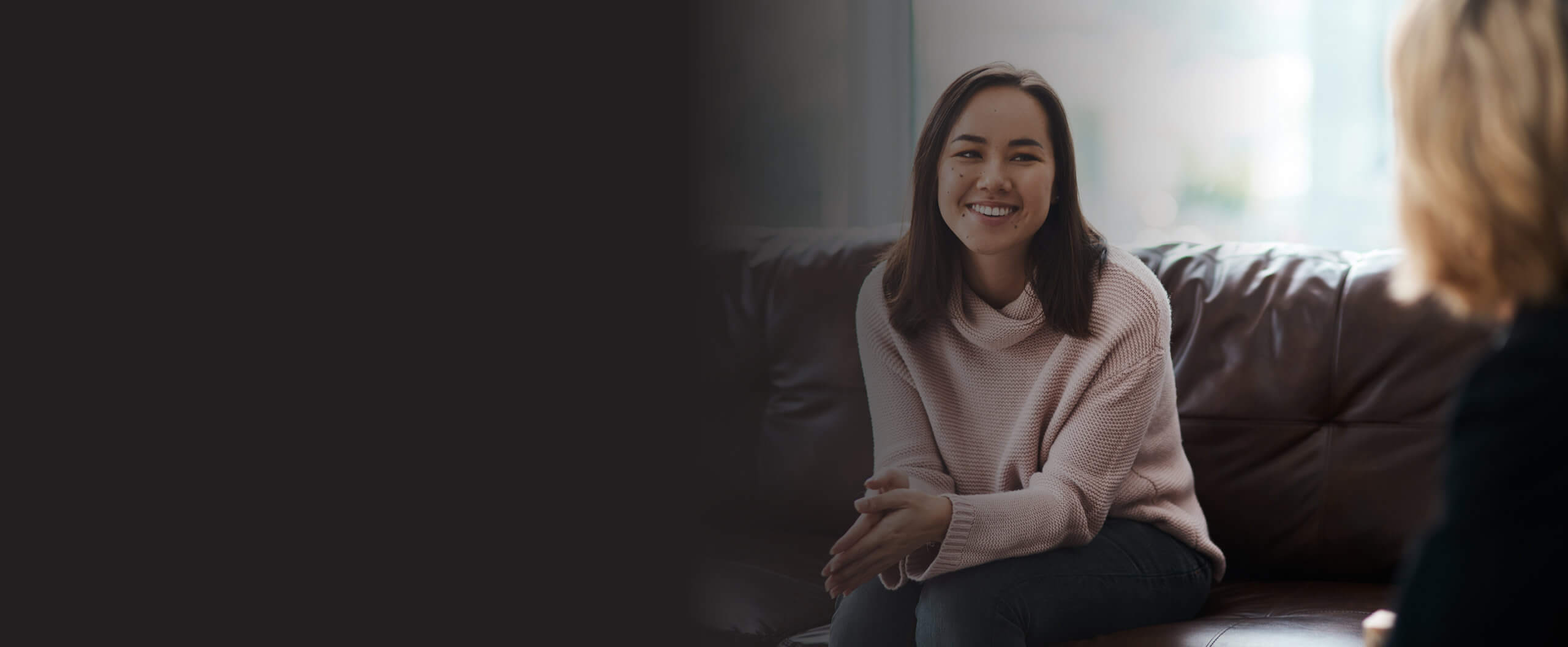 Woman smiling while sitting on a couch.