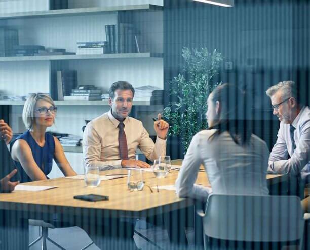 Coworkers communicating at desk seen through glass Group of work colleagues having a discussion at a desk.