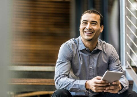 Person holding a digital tablet, smiling.