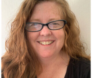 Woman wearing glasses and smiling at the camera