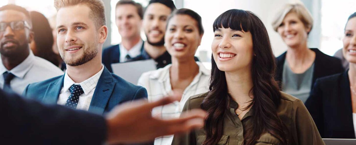 There's always something new to learn in business Diverse group of people sitting in a lecture, smiling.