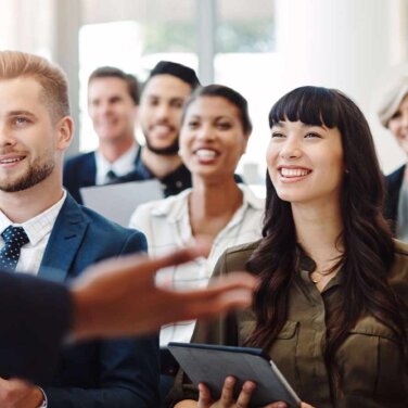 There's always something new to learn in business Diverse group of people sitting in a lecture, smiling.