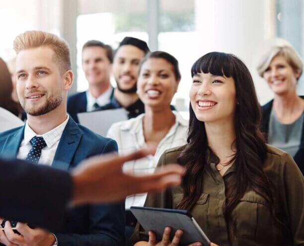 There's always something new to learn in business Diverse group of people sitting in a lecture, smiling.