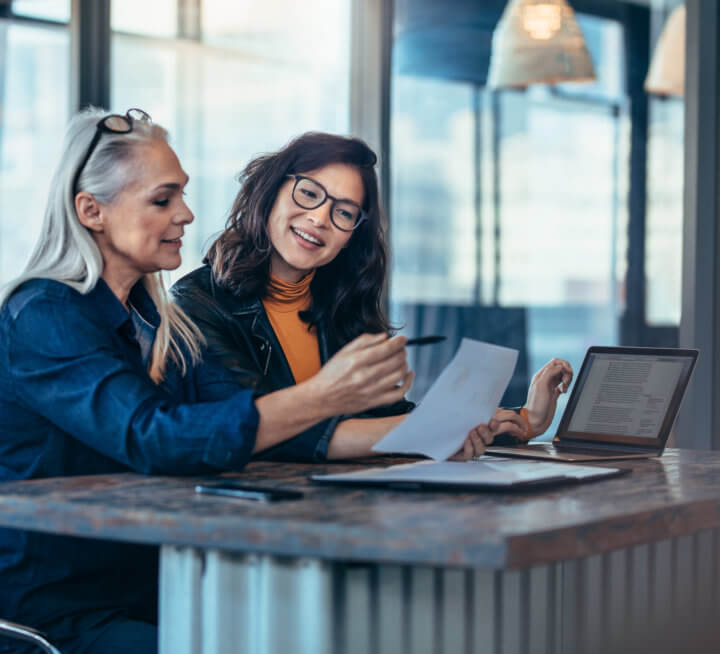 Two women analyzing documents at office