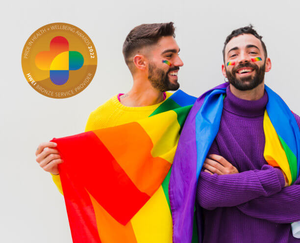 Two men with the Pride Flag draped around their shoulders.