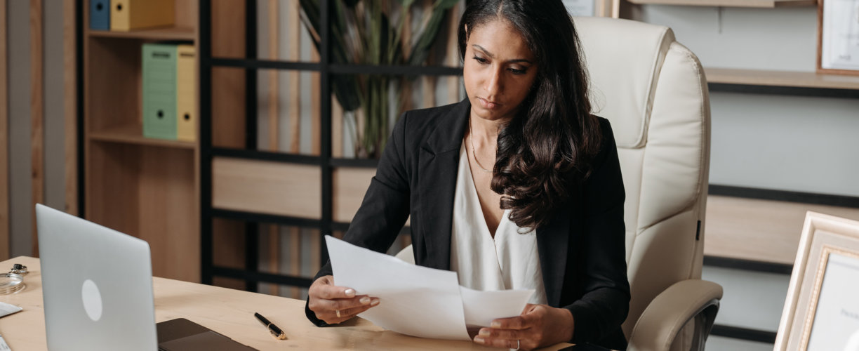 A woman sitting at a desk reviewing paperwork.