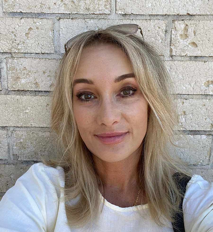 Allegra A headshot of a woman in front of a brick wall.