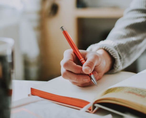 Application_Pen and Paper Close up of a student writing in a book.