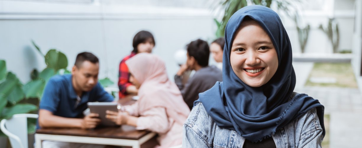 A woman smiling with other students in the background.