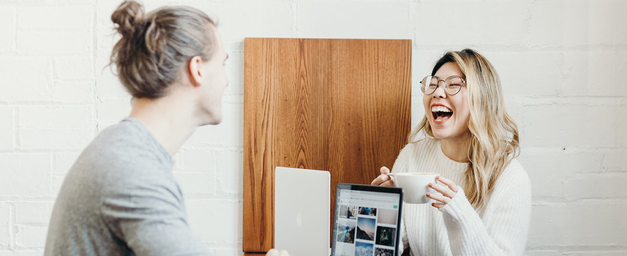 two people laughing ijn front of laptops