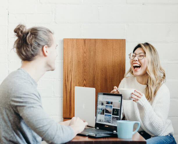 two people laughing ijn front of laptops