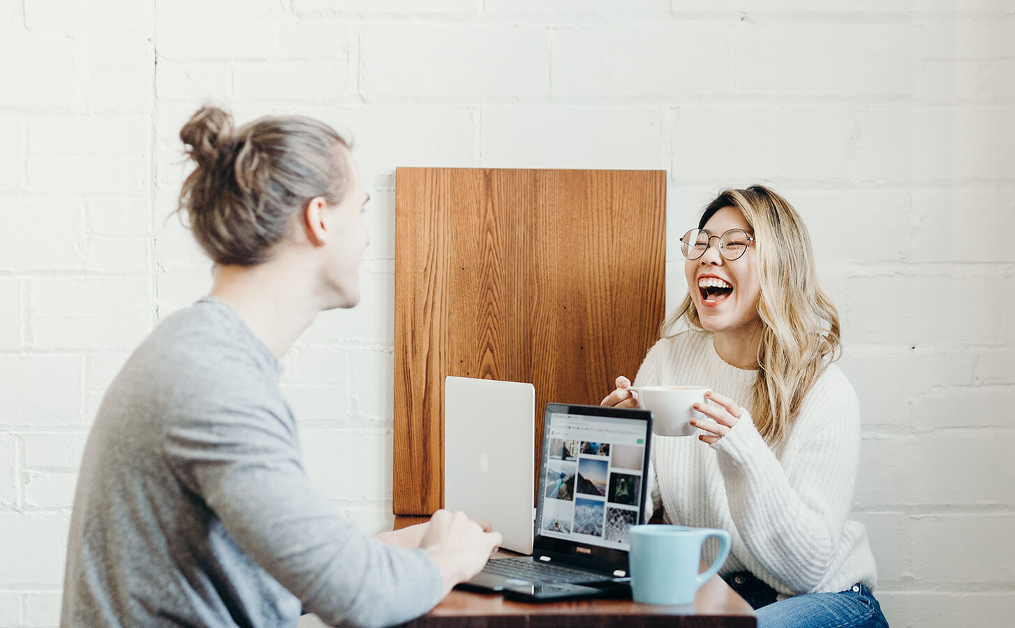 two people laughing ijn front of laptops