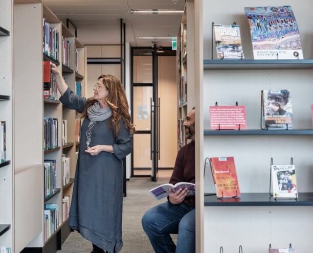 Woman reaching for book in library