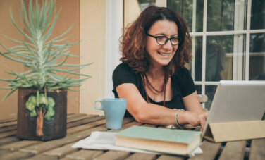 Middle aged woman studying at home with books and a tablet in front of her