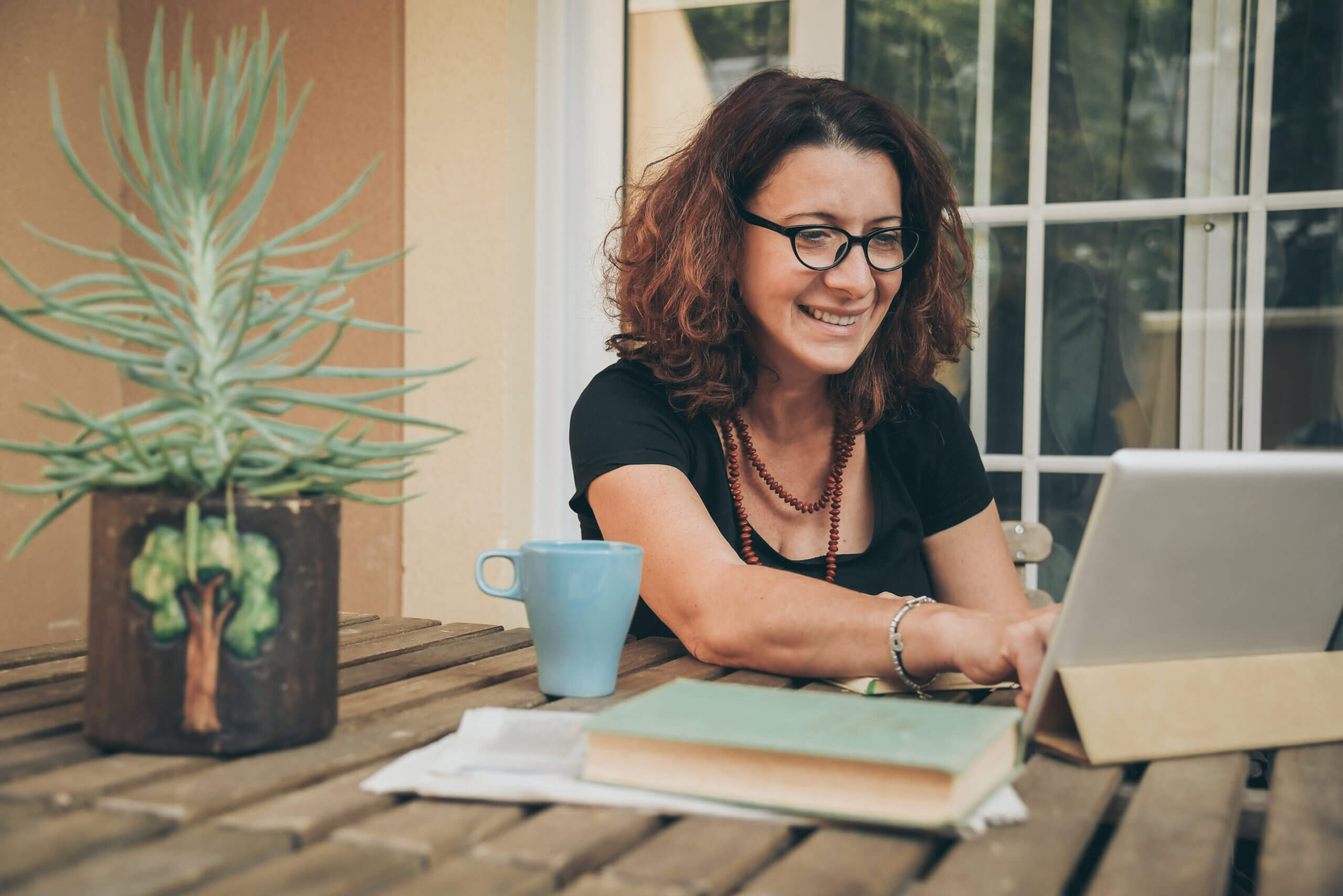 Middle aged woman studying at home with books and a tablet in front of her