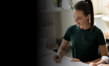 Young woman holding a pen being supervised by an older woman
