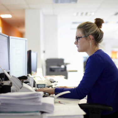 A woman sitting alone at a desk viewing two computer monitors ACAP Careers Design for Learning