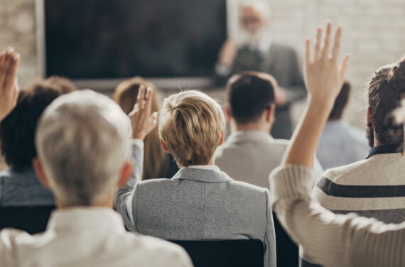 Rear view of a classroom with students holding their hands in the air ACAP Careers Law & Justice