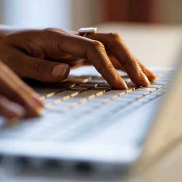 Close up view of a person's hands typing on a laptop ACAP Careers Sales & Admissions