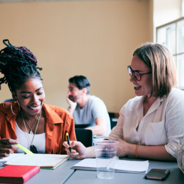 Two women smiling and working together in a classroom ACAP Careers counselling