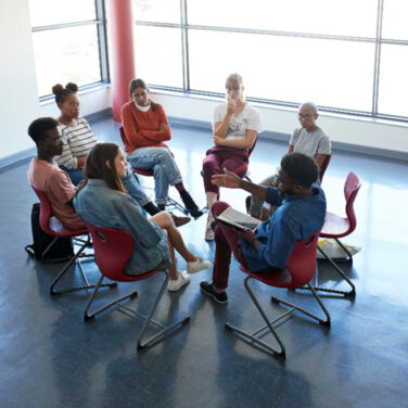 A support group sitting on chairs in a circle formation ACAP Careers social work