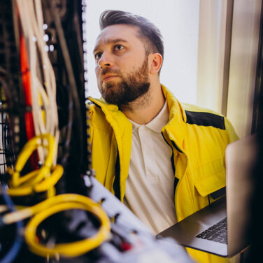 A male IT student with a yellow jacket assessing computer hardware