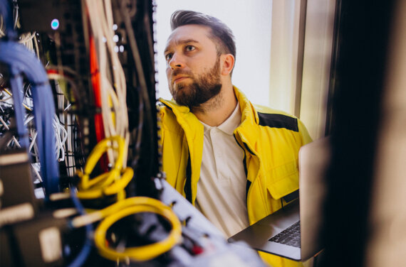 A male IT student with a yellow jacket assessing computer hardware