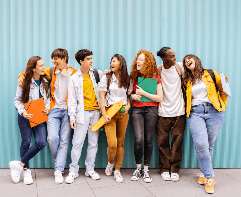 Seven students standing together in a row against a light blue wall