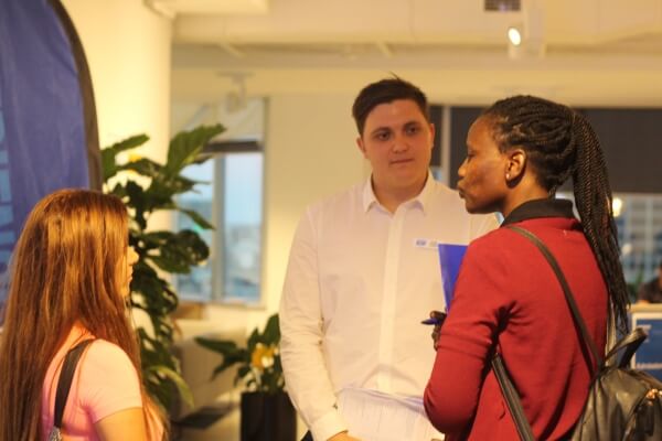 Three students standing and talking at a college information session