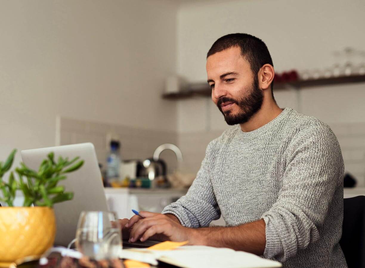 Man with short shaved hair working from a laptop at home