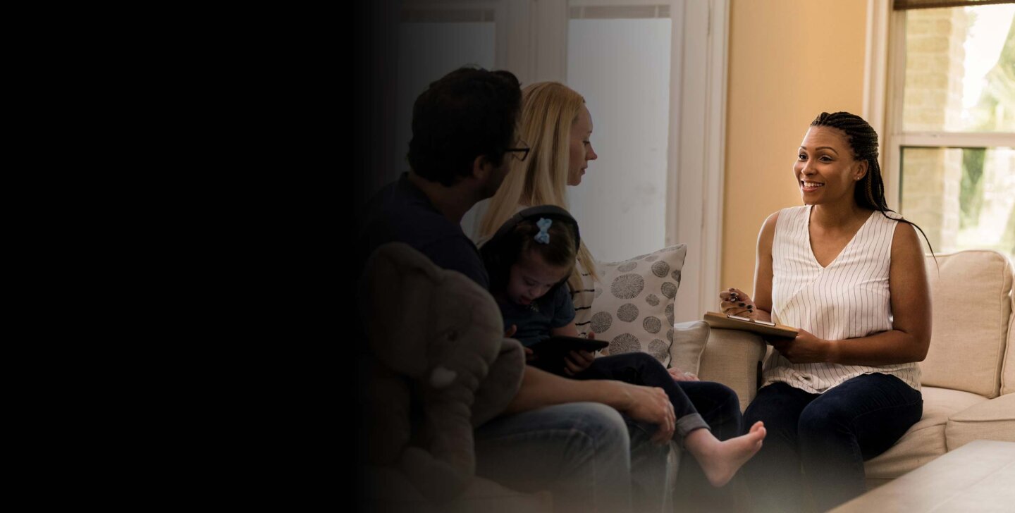 Master of Social Work (Qualifying) A female counsellor sitting on a chair with a clipboard, facing a couple with a child sitting on the man's lap | Master of Social Work (Qualifying)