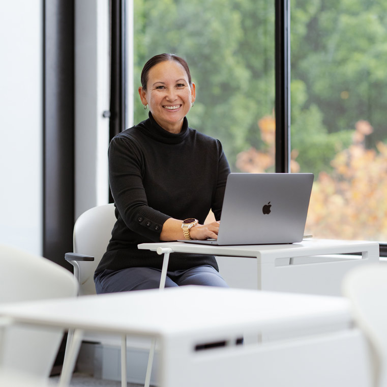 A woman working on a laptop in a classroom - Online Information Sessions (761x761)