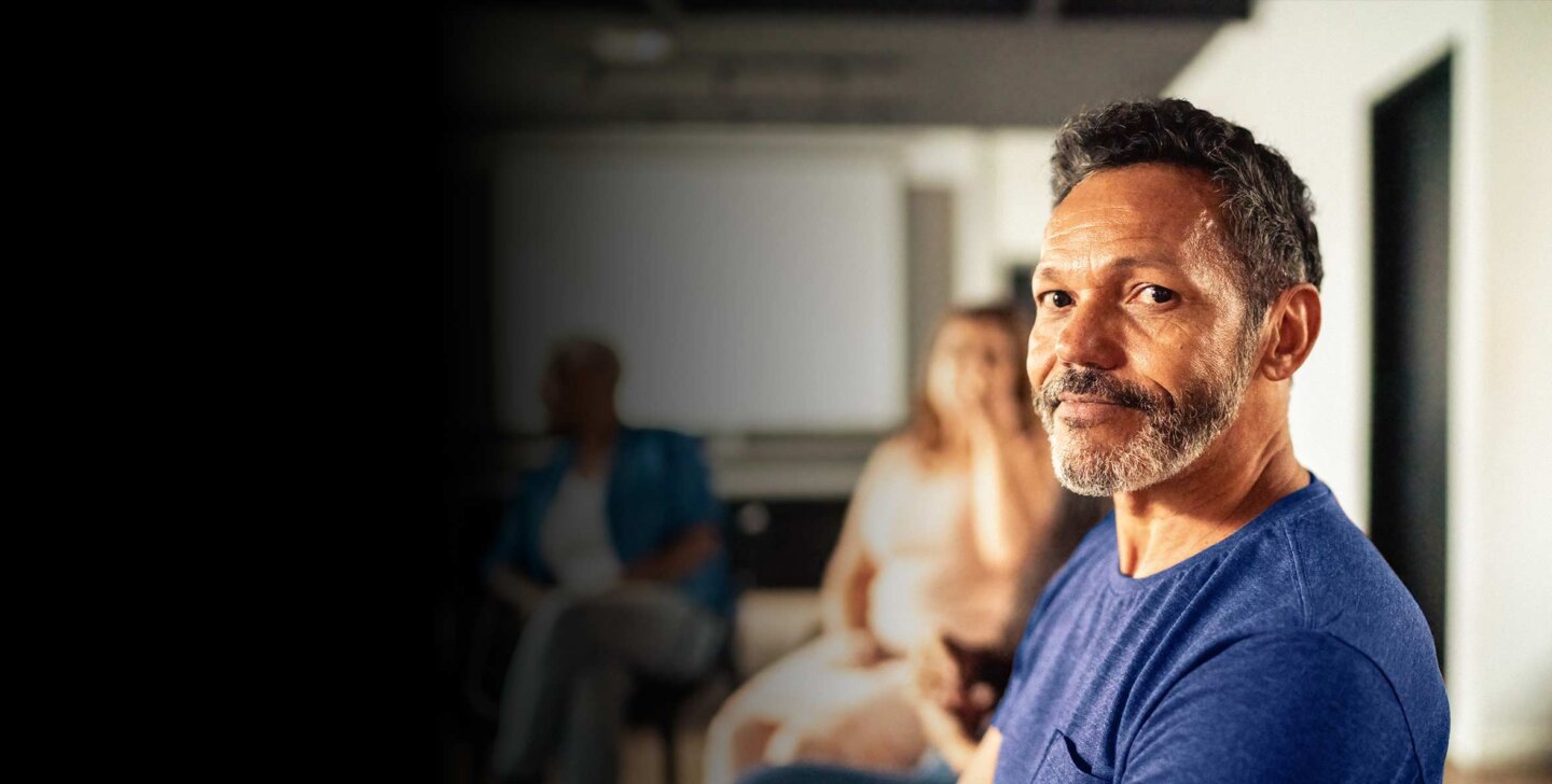 Man sitting in a counselling support group, facing towards camera